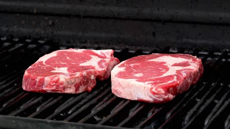 Two-raw-rib-eye-steaks-getting-ready-to-cook-on-a-grill