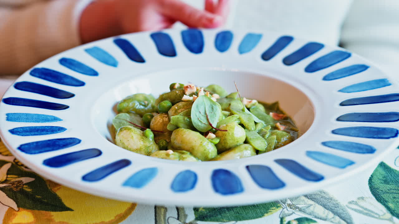 Woman eating gnocchi with pesto at an Italian restaurant