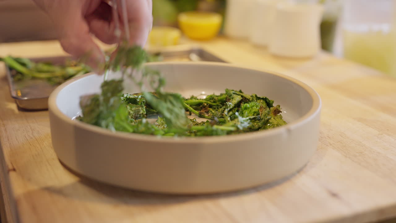 Primo piano di verdure cotte impiattate nella cucina di un ristorante. Lo chef completa un piatto caldo con guarnizioni e salsa, mettendo in mostra precisione culinaria professionale, consistenza e presentazione raffinata.