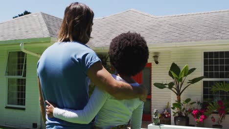 Rear-view-of-happy-mixed-race-couple-looking-at-their-new-house