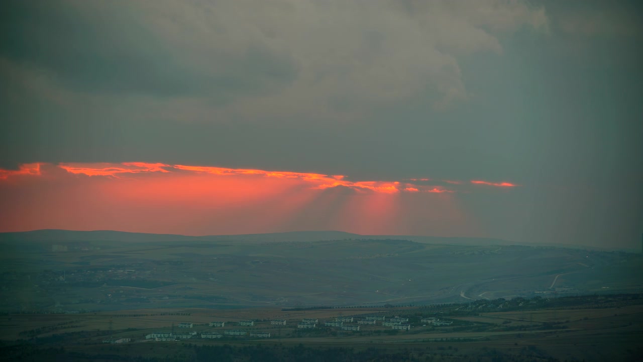 Dramatic Sunset Over Rolling Hills and Distant Village