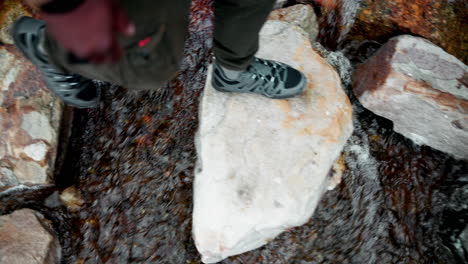 person crossing a stream on stepping stones