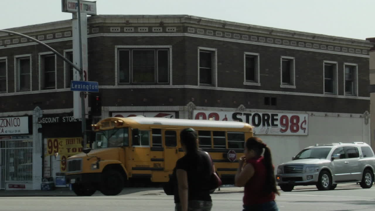 보행자가 98센트 매장 배경으로 걸어갈 때 교통이 도시 거리를 이동합니다.