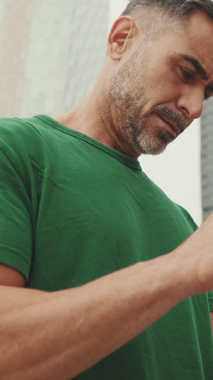 Man with green shirt holding a smartphone