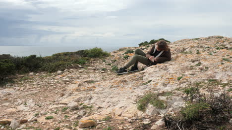 Boy-traveler-hitting-rocks-when-exploring-Cape-St-Vincent-in-Portugal