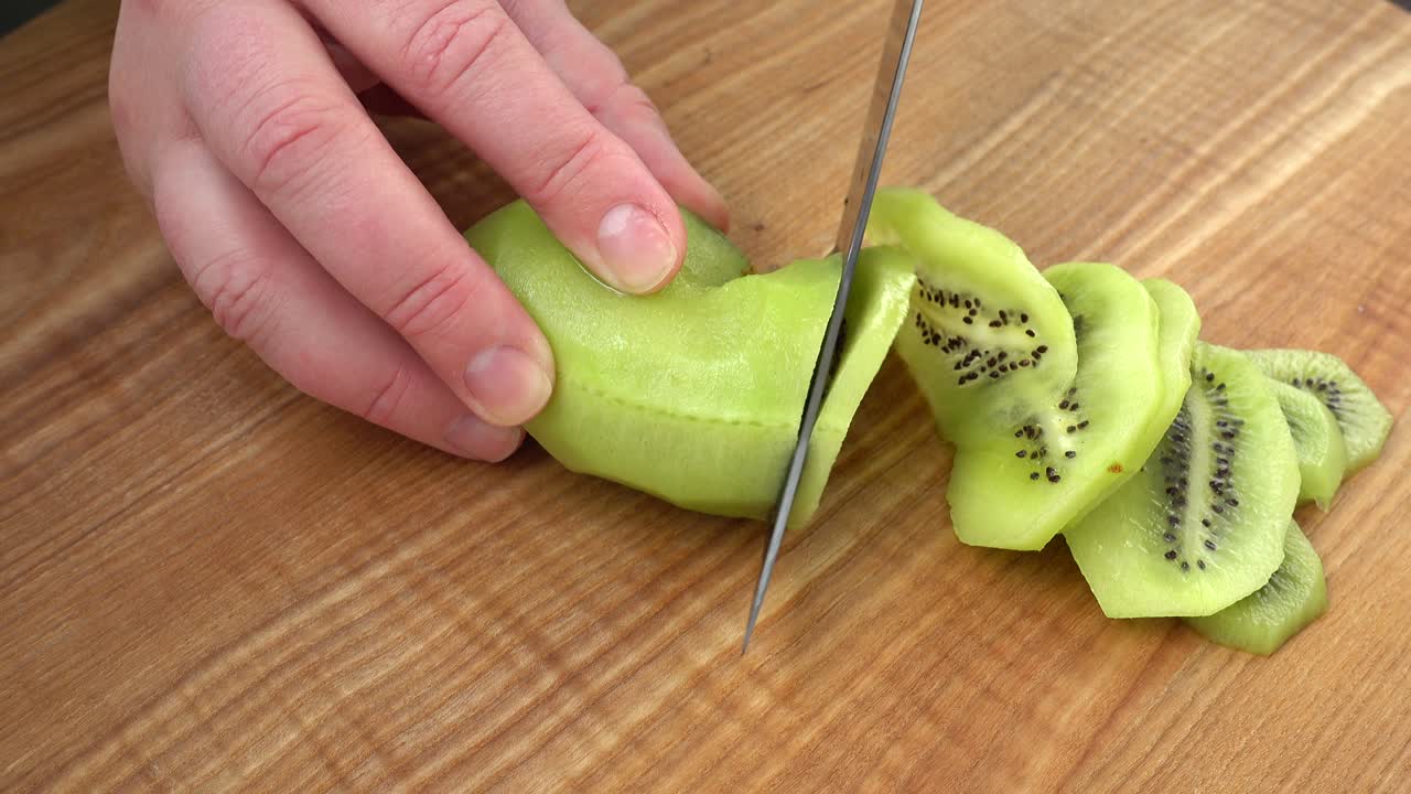 Aşçı bir kivinin parçalarını kesiyor. Yemek çekimi.