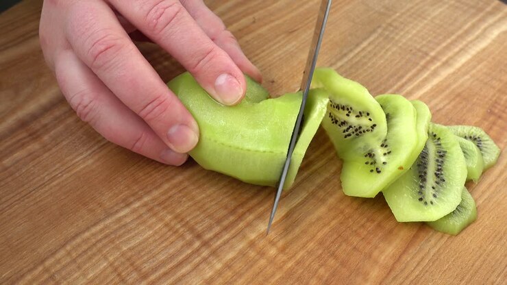 The cook cuts pieces of a kiwi. Cooking shooting