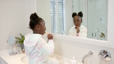 chica afroamericana cepillándose los dientes en el baño, cámara lenta