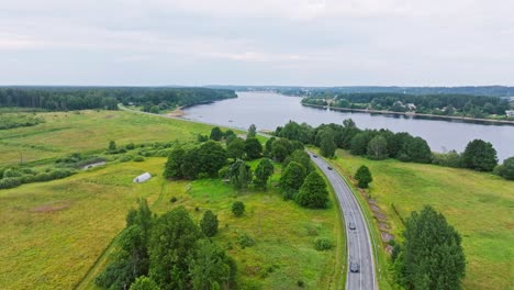 Overcast aerial of Latvian countryside with river, road, and visible homestead