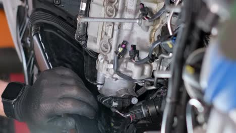 close-up of a mechanic's hand working on an engine's electrical system