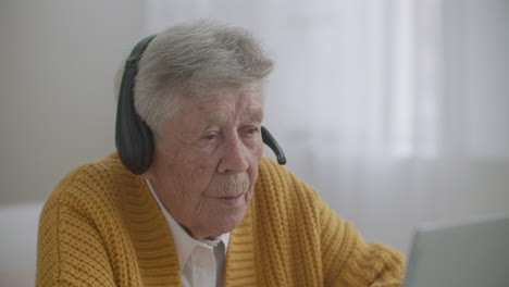 elderly-Woman-are-using-laptop-to-make-video-call-talking-gesturing-showing-thumbs-up-hand-gesture-indoors.-Old-woman-and-modern-devices-concept.