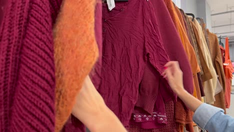 young caucasian woman looking at clothing, hanging on hangers. shopping in women’s clothing store. hd video