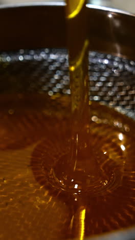 fresh honey flowing onto the metal sieve. organic product filtration right after extracting. close up. top view. vertical video