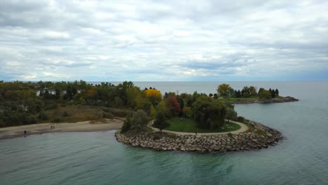 Aerial-view-of-the-Scarborough-Bluffs,-Canada,-located-in-Lake-Ontario,-while-some-tourists-are-walking-in-a-beach