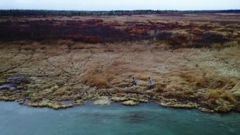 Professional-fly-fishing-guide-and-client-walking-along-the-Naknek-River-in-tall-prairie-grass