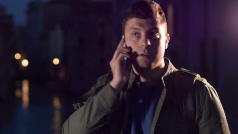 man talking on phone at night in city