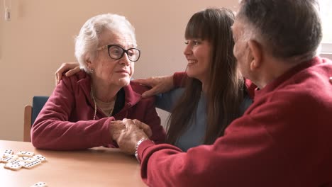 happy elderly grandparents kissing granddaughter in retirement home