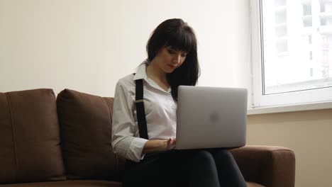 young woman using laptop at home sitting on sofa