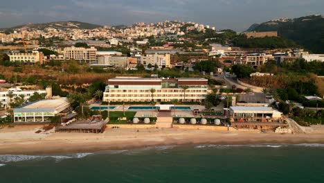 drone shot flying backwards over sand beach and seafront city in middle east
