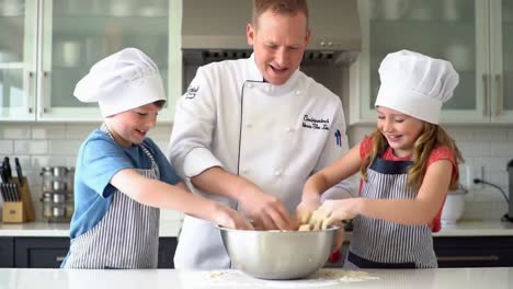 professional chef teaching happy children how to bake in a modern kitchen
