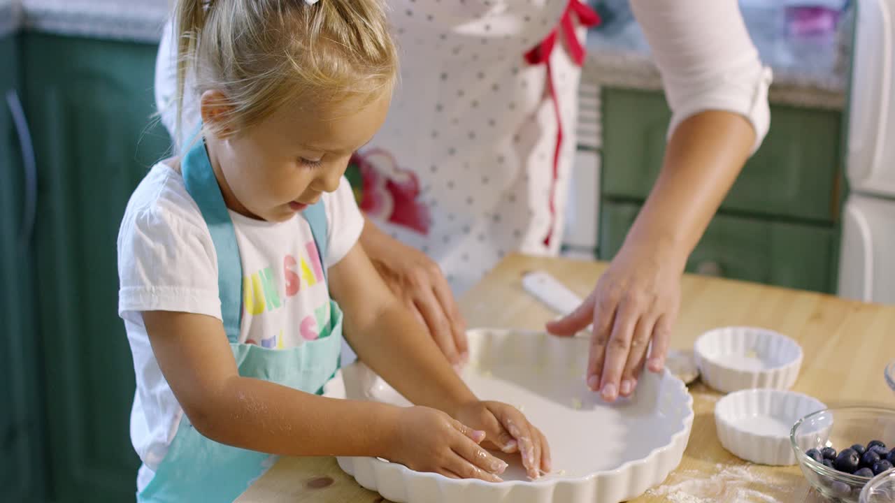Cute little girl greasing a baking dish