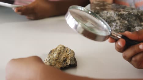 school kids using magnifying glass over rock