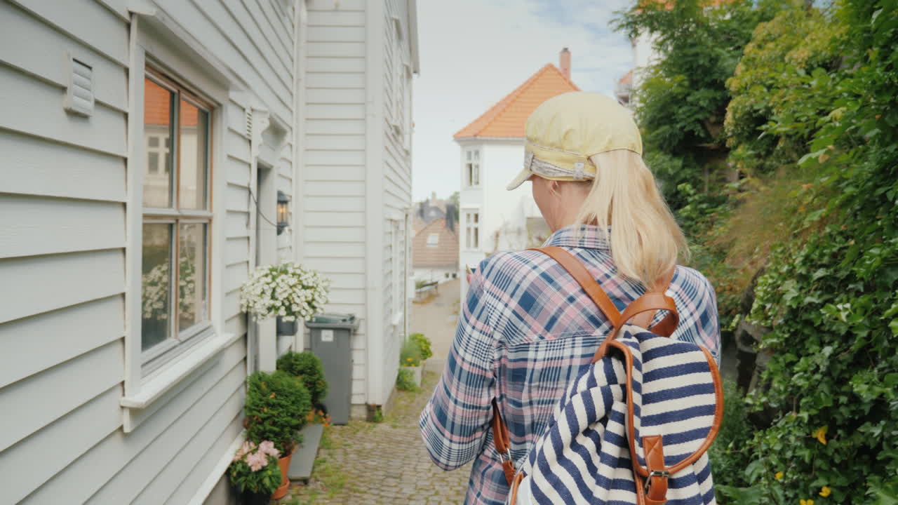 женщина идет по узкой улице старого города пользуется навигатором на смартфоне город б