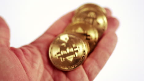 moneda criptográfica bitcoin - mano sosteniendo y volteando monedas bitcoin doradas y luego colocadas sobre la mesa