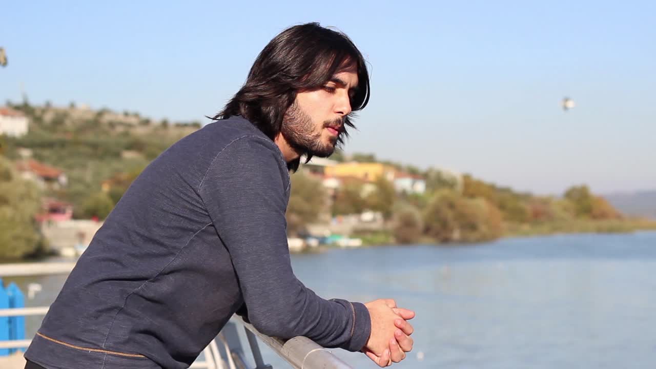 외로운  ⁇ 만적인 남자가 바다를 바라보고 있습니다.