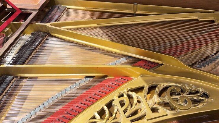 Ornate antique grand piano internal mechanism with strings and gilded iron frame