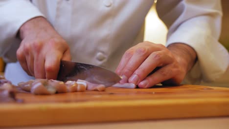 the cook cuts the squid on a wooden board