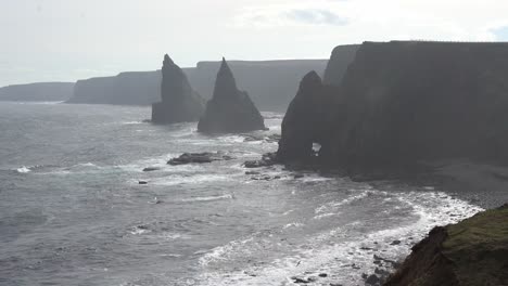 wild beauty of the scottish coast with sight of duncansby stacks rising majestically from the sea, adorned with an abundance of nesting birds that gracefully soar through the air