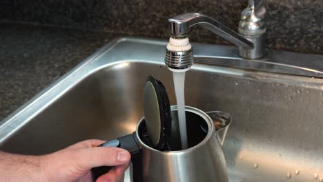 shot of a person filling up a kettle to boil water for coffee or tea