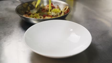 chef profesional en primer plano plato de tagliatelle ai frutti di mare plato clásico mediterráneo en la cocina de un restaurante