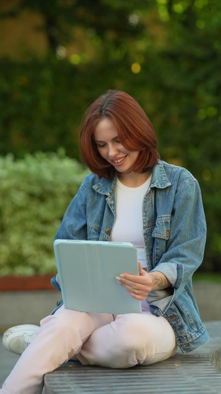 Giovane donna che usa un tablet in un parco
