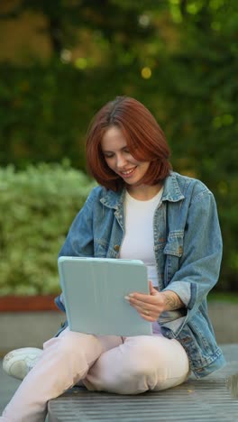 mujer joven que usa la tableta en un parque