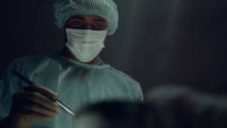 Portrait-african-american-surgeon-performing-surgical-operation-in-clinic-room.