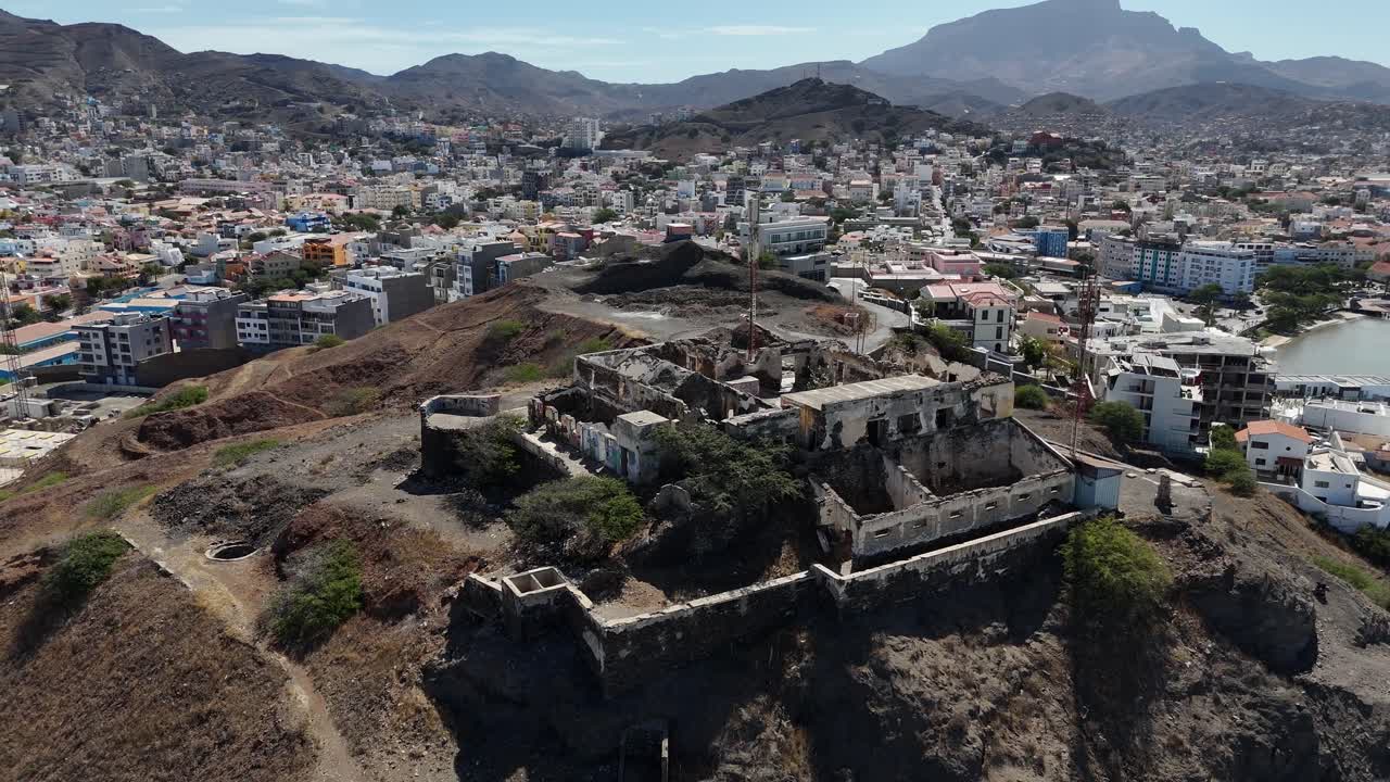 Ruinas del Fortim d'El Rei en primer plano con el colorido paisaje urbano, el puerto y las montañas volcánicas con vistas a la ciudad de Mindelo en la isla de Sao Vicente, Cabo Verde