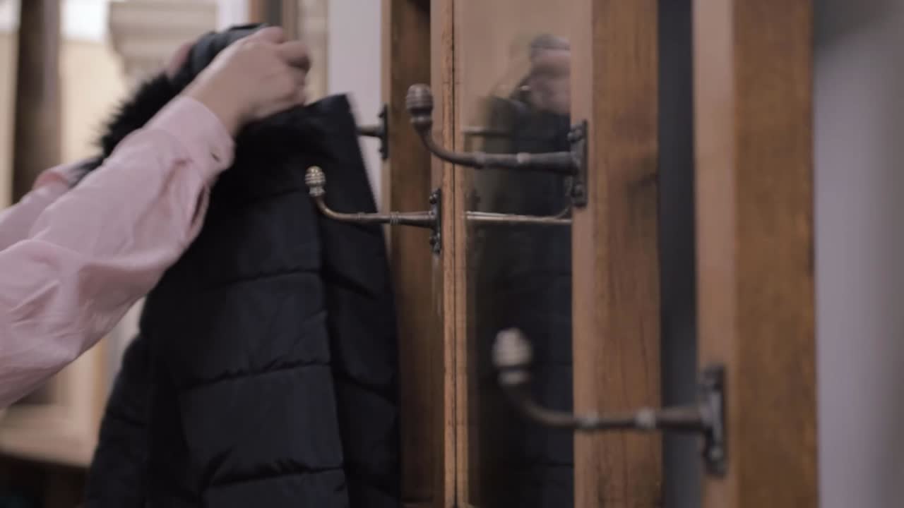 Woman gets her coat  hanging on coat hanger and walks away