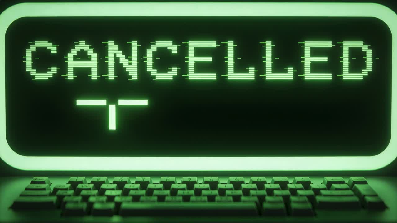 Displaying CRT green monitor refreshing and animating cursor over CANCELLED at desk with keyboard