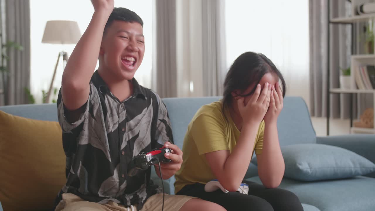 Asian Children With Joystick Game Play Video Game On Tv, Boy Celebrating Victory And Girl Disappointed