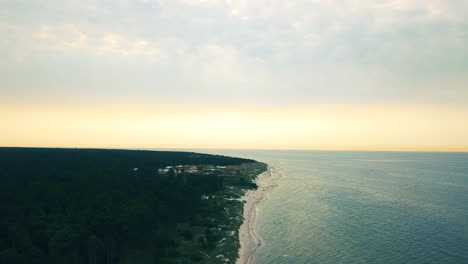 drone-descending-above-Loederupps-Strandbad-beach-in-sweden,-heading-towards-the-morning-sun