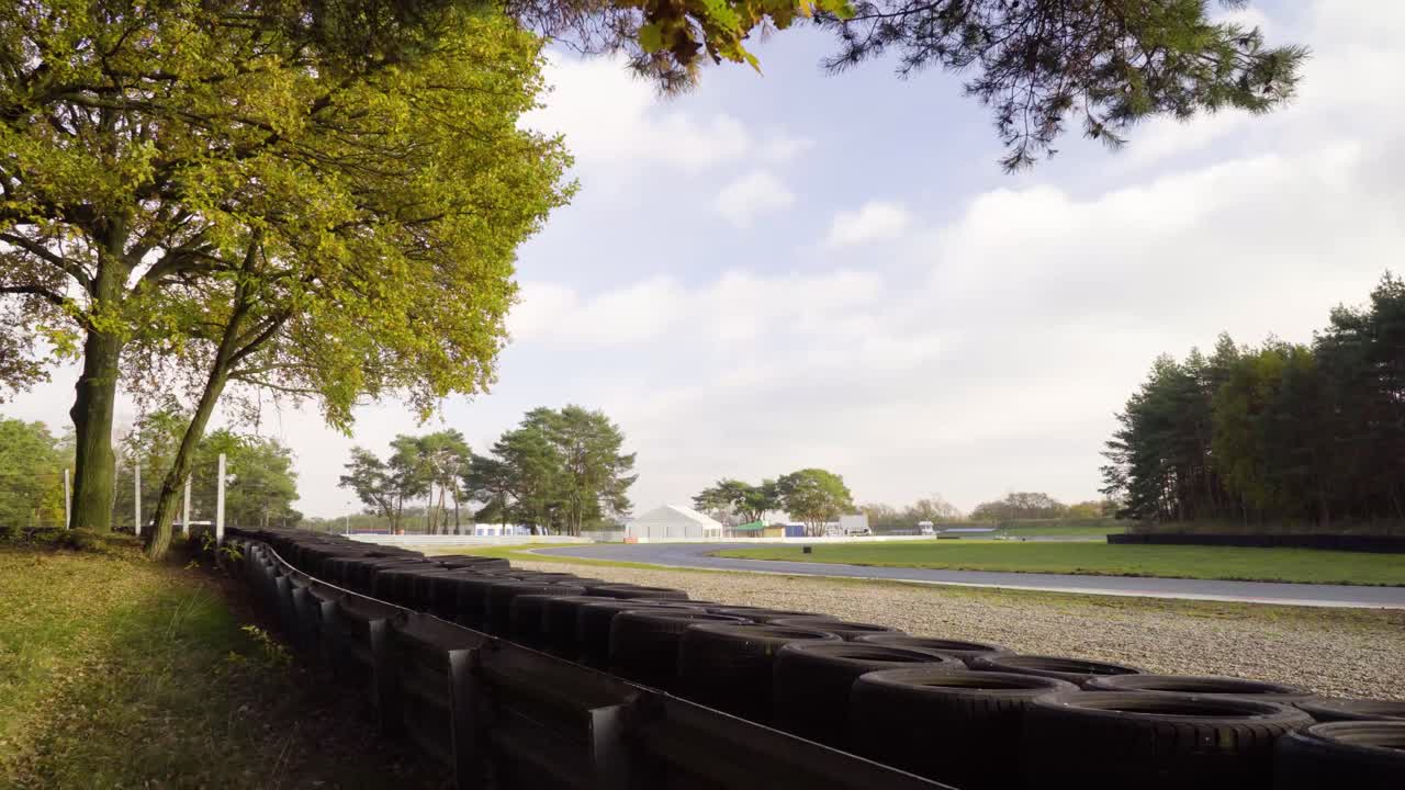 4k의 푸른 하늘과 구름이 있는 황금시간대에 타이어 벽이 있는 경주 트랙의 빈 회전 곡선