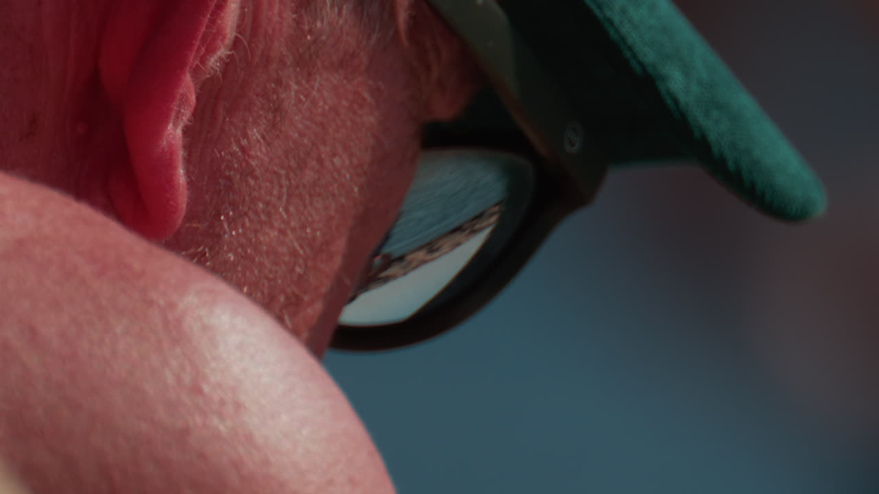 Cannes, France - October 10, 2025: Close up of an elderly man wearing a green cap and sunglasses, sitting by the sea
