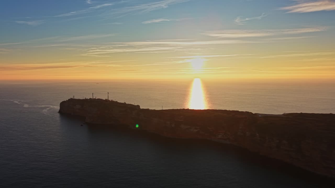 Pôr do sol sobre o oceano, com o reflexo nas falésias da costa