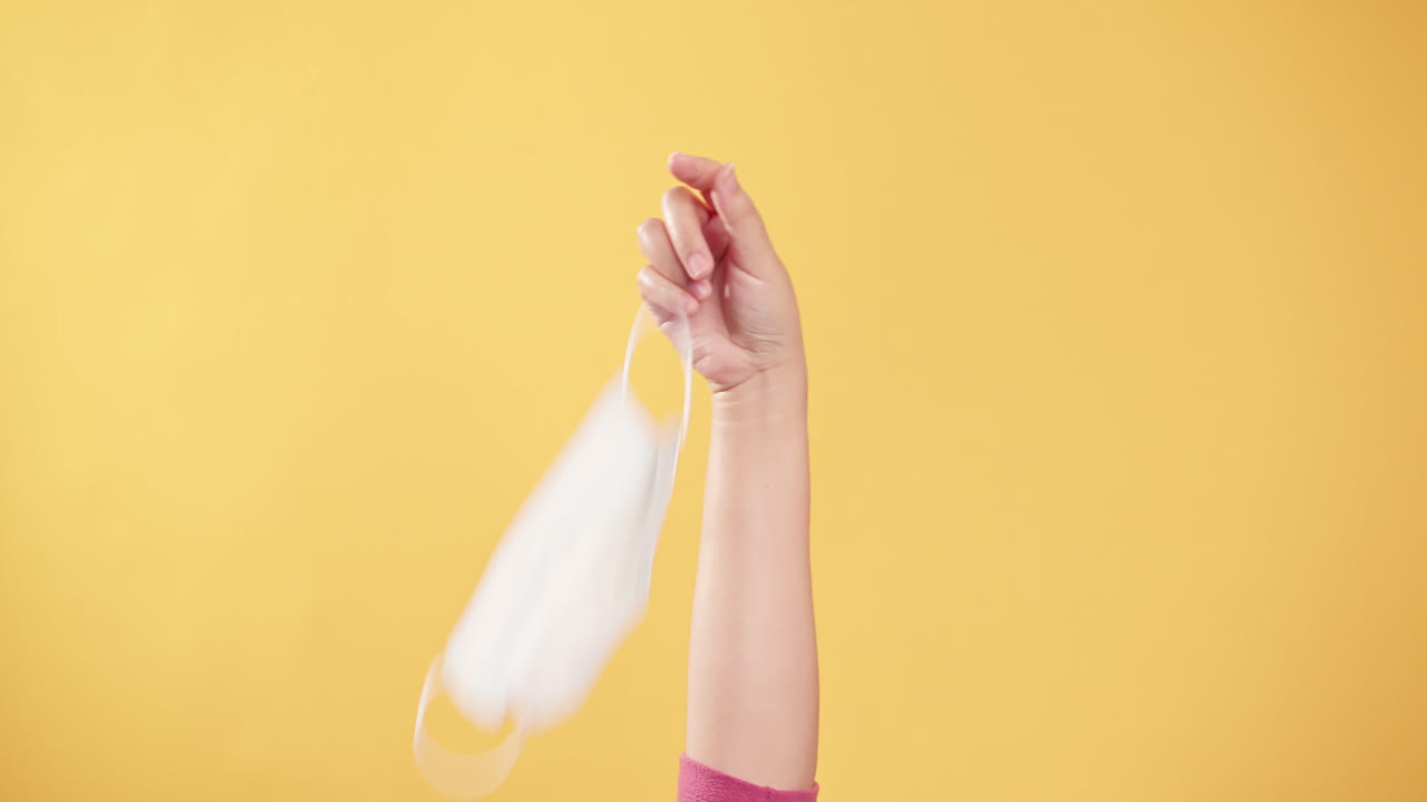 civid-19 상황이 노란색 배경으로 해결된 후 보호 마스크를 손에 들고 신선한 공기를 마시기 위해 벗습니다.