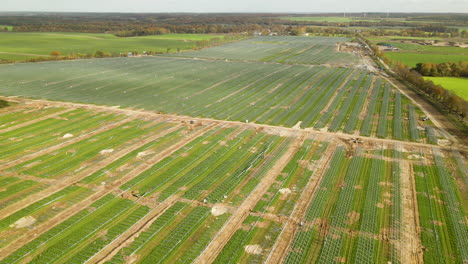 aerial shot of large of eco friendly solar energy farm during construction phase on rural farm field in poland - mounting racks substructure for solar panels