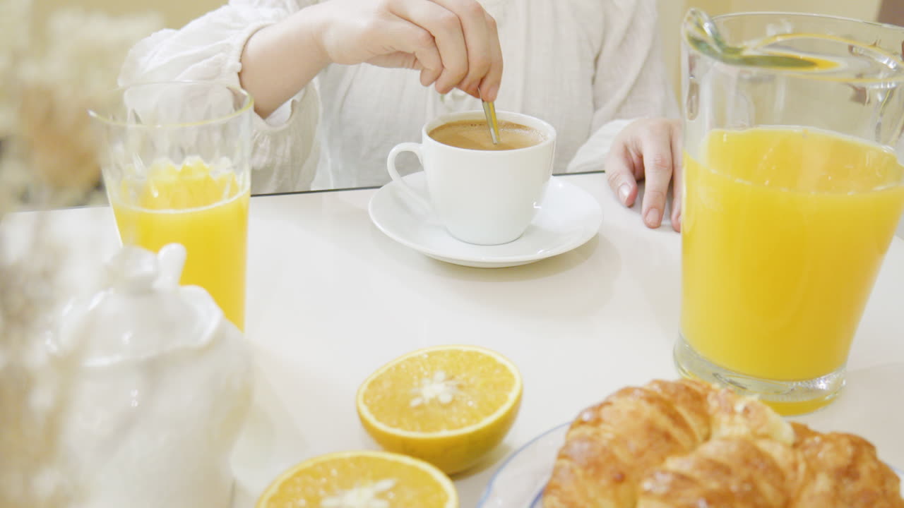 앉아있는 여자가 컵에서 커피를  ⁇ 고 뷔페 테이블에서 마시고 있습니다.