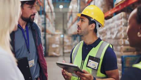 warehouse workers discussing inventory using a tablet