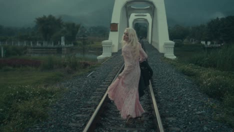 woman walking on train tracks on a bridge